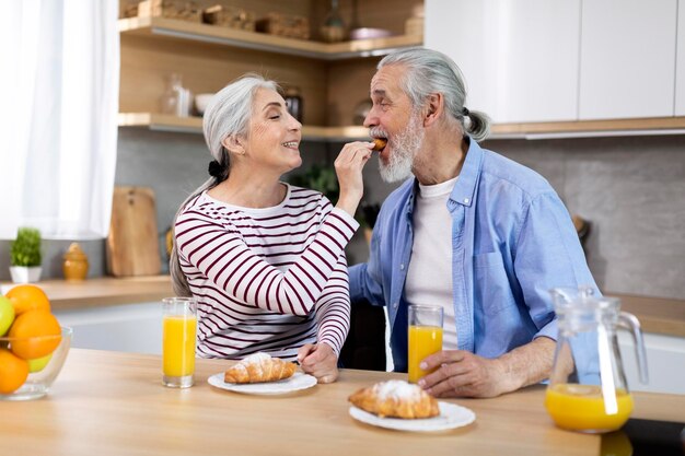 Romantici coniugi anziani che fanno colazione insieme in cucina a casa