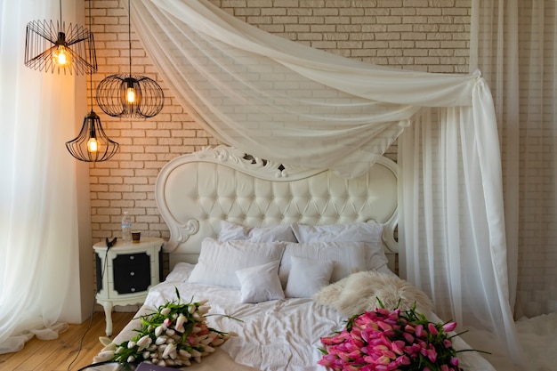 Romantic setting in the bedroom with white furniture and a four-poster bed