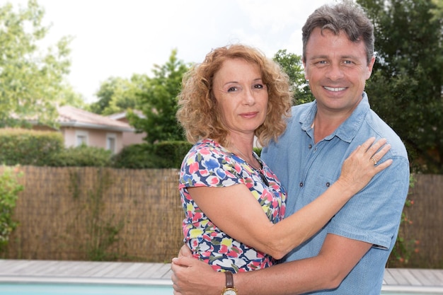 Coppia romantica e sorridente in piedi vicino alla piscina