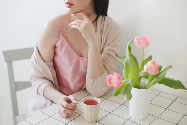 romantic spring portrait of a young woman with tulips at home