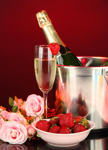 Romantic still life with champagne, strawberry and pink roses, on dark color background