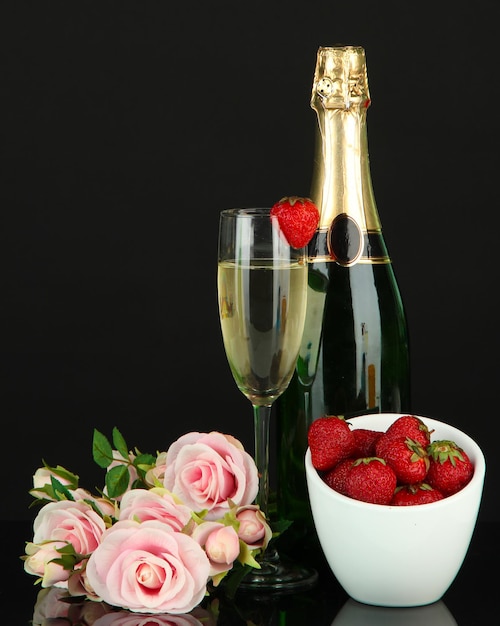 Romantic still life with champagne, strawberry and pink roses, isolated on black