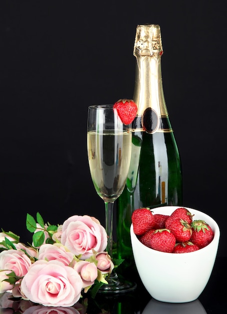 Romantic still life with champagne, strawberry and pink roses, isolated on black