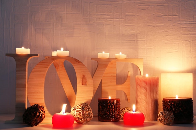 Romantic still life with word LOVE and candle lights on mantelpiece and white wall background