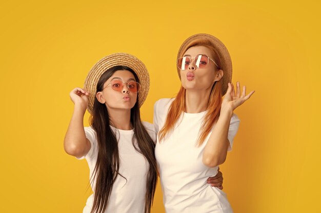 Romantic summer mood happy stylish mother and daughter posing at studio yellow background wearing