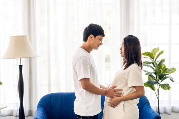 로맨틱 한 달콤한 아시아 부부 남편 포옹 하 고 웃는 아름다움 아시아 임신 아내남자 여자 임신을 기대 하 고 집에서 뱃속에 아기를 안고