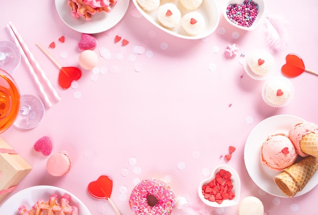 Romantic sweet dessert table with pink waffles donut ice cream macaron lollipop candies Valentine's day concept Top view Copy space