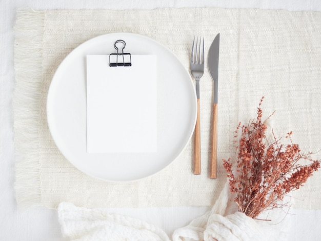 メニュー用の白い紙を用いた明るい色の空き皿でロマンチックなテーブルプレートを設定します