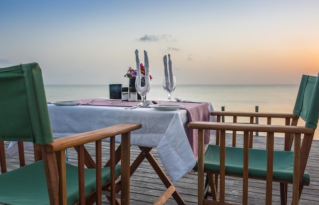 바다 경치를 배경으로 한 낭만적인 테이블 설정 해변의 레스토랑 열대 리조트의 일몰