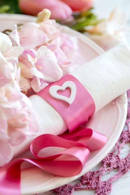 Romantic table setting with flowers and pink ribbon close up