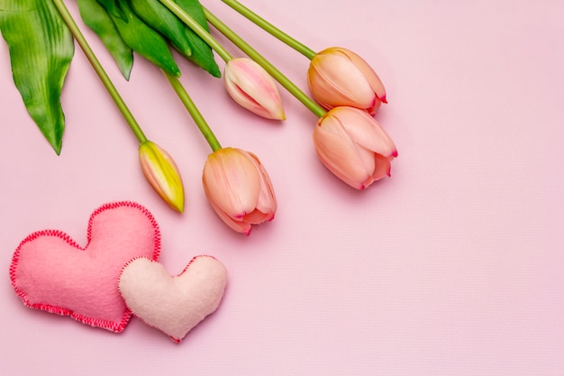 Romantic tulips bouquet on pink table with hearts. Valentine concept