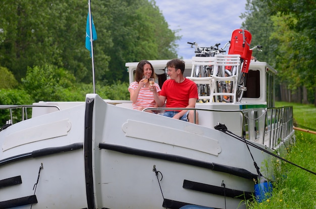 Romantic vacation, travel on barge boat in canal, happy couple having fun on river cruise in houseboat