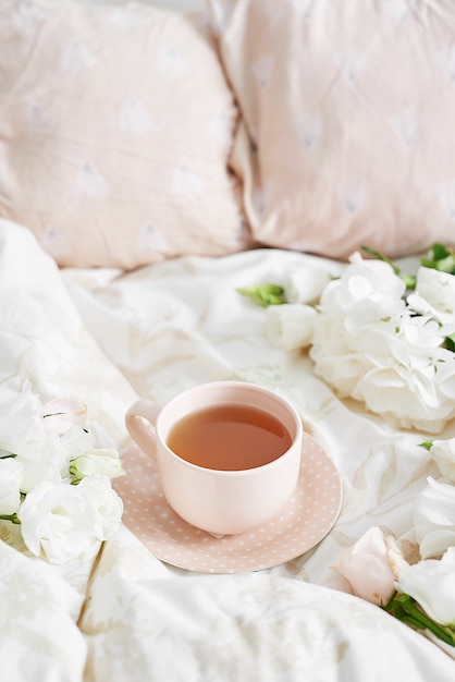 Romantic valentine's day Breakfast in bed with tea cup and flowers on bed