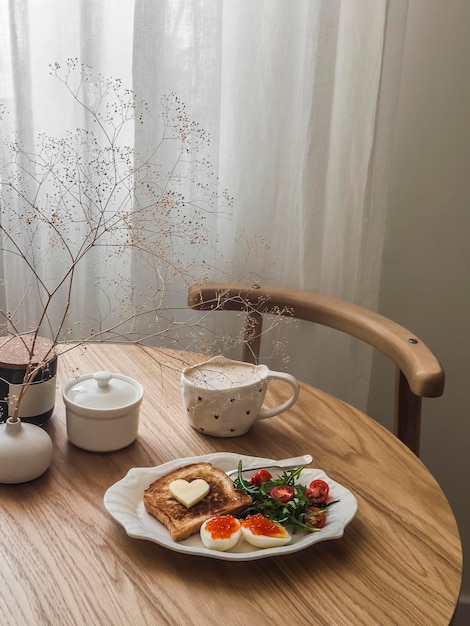 Романтический завтрак на День святого Валентина, бранч, кофе, тост, яйца с красной икрой и салат на круглом деревянном столе.