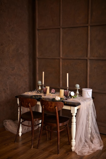 Romantic or Wedding dinner setup or Holiday table setting, brown, pink and gold decoration with candles and garland light.