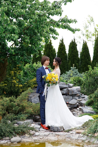 Romantic wedding moment, couple of newlyweds happy portrait, bride and groom hug while on a walk in the park