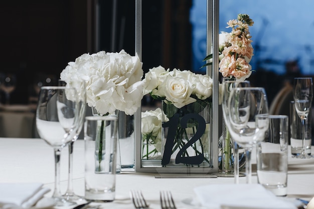 Romantic wedding table top layout decor with large lush floral bouquets including white roses ranunculus persian buttercups white orchids and candles