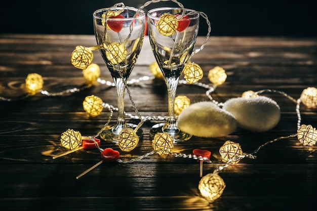 Foto bicchieri di vino romantici con cuori per il giorno di san valentino appuntamento romantico e cena luci accoglienti fondo in legno cartolina di vacanza concetto di amore