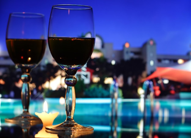 Romantic wineglasses on a glass table at night hotel