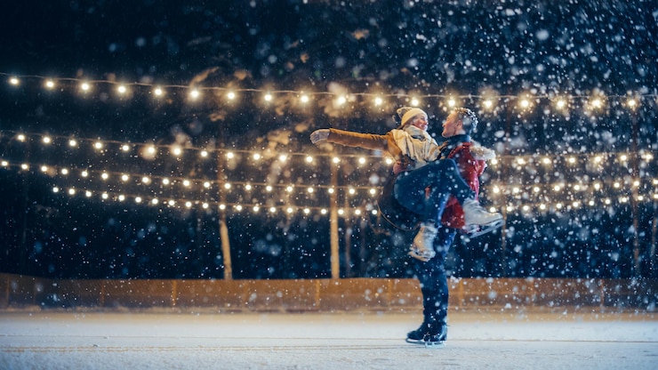 Photo romantic winter snowy evening ice skating couple having fun on ice rink pair skating boyfrined lifts his beautiful girlfriend and spins love dance embrace figure skate wide shot