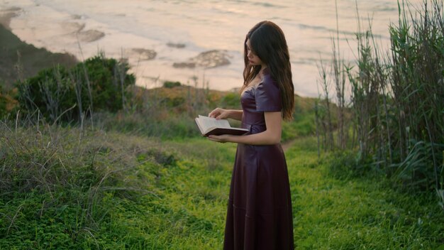 Romantic woman looking book turning pages in beautiful ocean overcast day