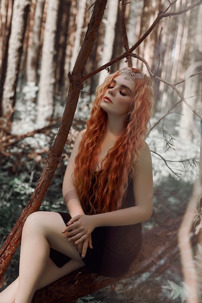 Romantic woman with red hair lying in the grass in the woods