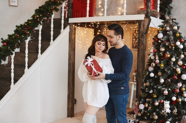 Romantic young couple exchanging christmas gifts in the living room decorated for new year holidays