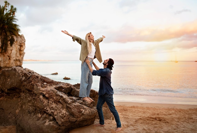 Romantic young couple having fun together at the beach on sunset