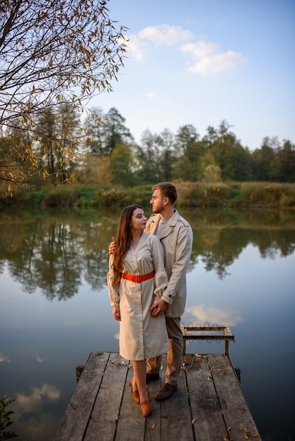 Una giovane coppia romantica si erge su un molo vicino al lago. autunno.