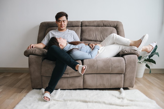 romantic young happy asian couple lying at home in sofa resting talking and having fun together