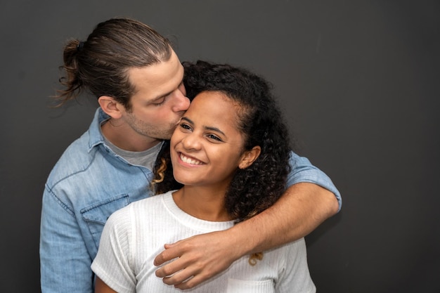 写真 ロマンチックな若い幸せなカップルの白人男性とアフリカ系アメリカ人の女性は笑顔で、黒い背景の上のバレンタインデーで一緒に楽しんでください