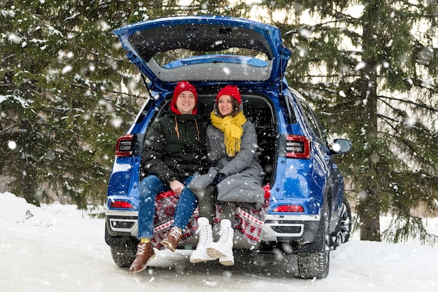 Romantic young hipster couple hugging while sitting in car trunk. Love, valentines day