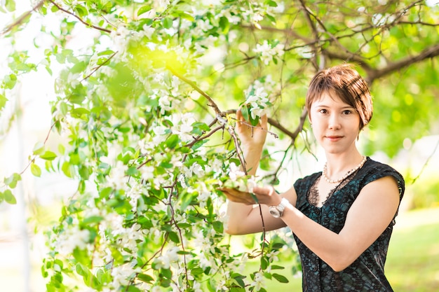 Giardino romantico della giovane donna in primavera fra il fiore della mela