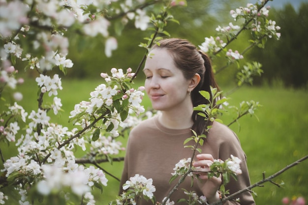 リンゴの花の中で春の庭でロマンチックな若い女性