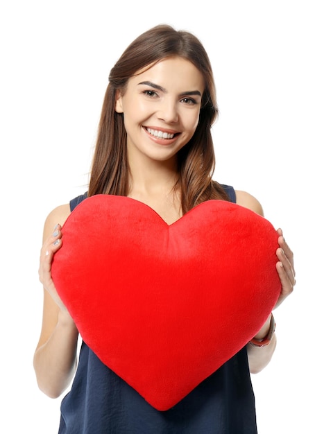 Romantic young woman with heartshaped pillow on white background