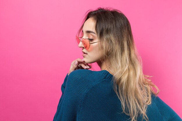 Romantisch blondharig meisje in trendy hartglazen poseren met een verlegen glimlach