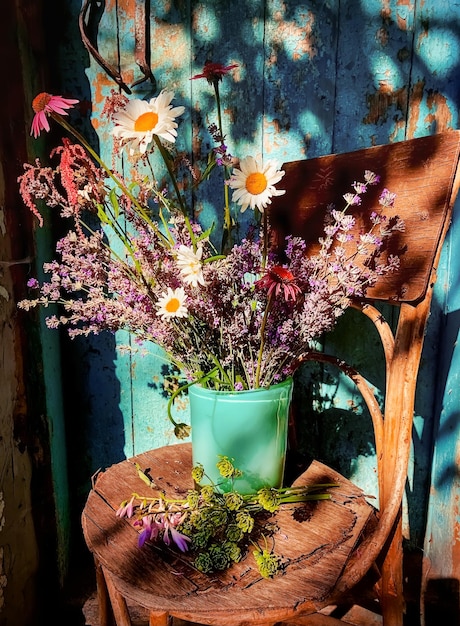 Romantisch boeket met lavendel, kamille, echinocea, astilbe, hosta en pastinaak in een retrostijl op de binnenplaats tegen de achtergrond van een blauwe oude deur