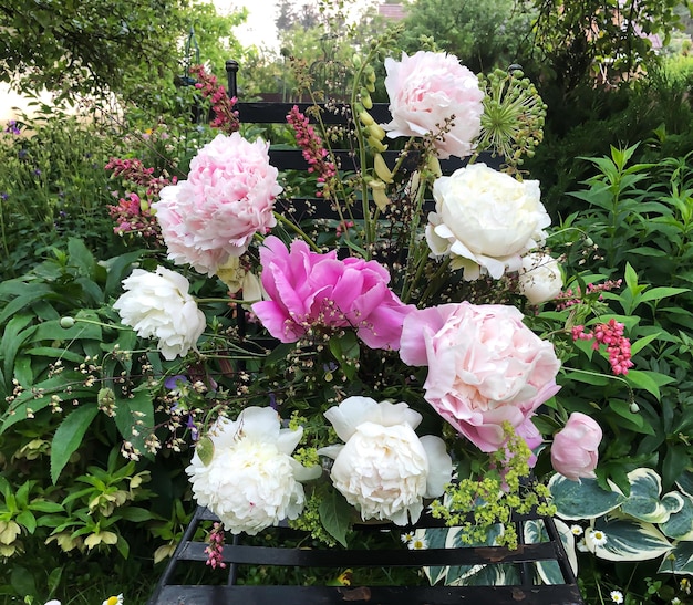 Romantisch boeket met pioenrozen geykhera allium hortensia en vingerhoedskruid Zomerboeketten van boerderijbloemen buiten in de tuin Floristiek kunst van bloemen arrangementen