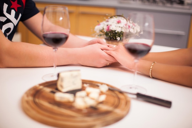 Romantisch diner met een wijnliefhebbend paar close-up hand in hand
