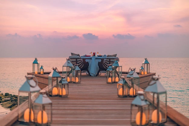 Romantisch diner op het strand met zonsondergang, kaarsen met palmbladeren en avondrood en zee. Geweldig