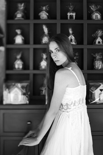 Romantisch elegant meisje in witte jurk poseren over versierde muur
