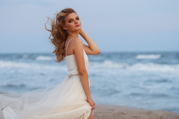 romantisch meisje alleen op de oceaan. haar jurk ontwikkelt de wind. portret met onscherpe achtergrond.