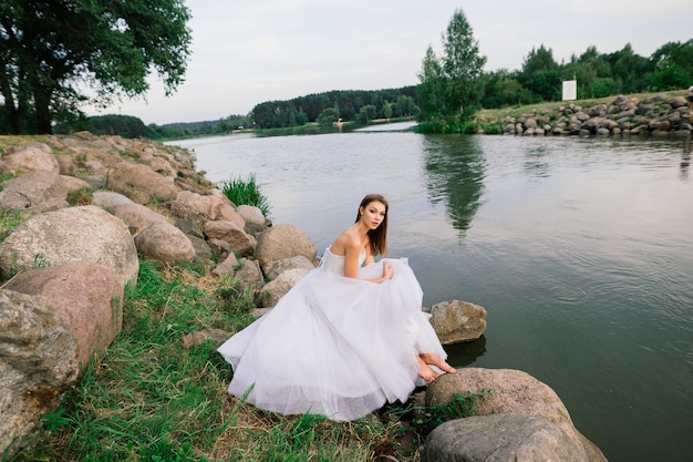 Romantisch meisje in een tedere witte jurk aan de oever van een meer
