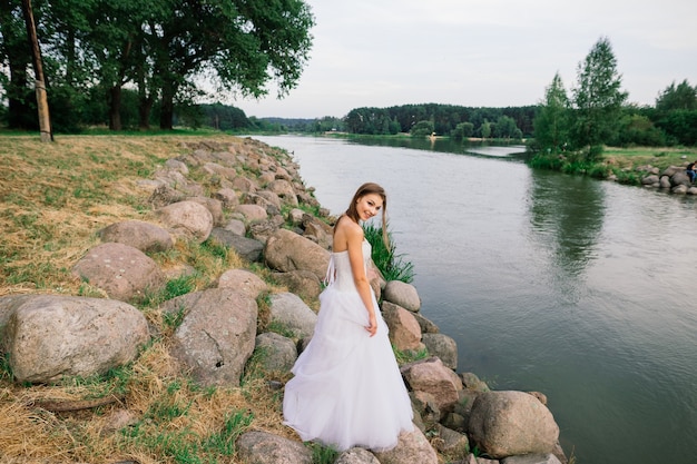 Romantisch meisje in een tedere witte jurk aan de oever van een meer