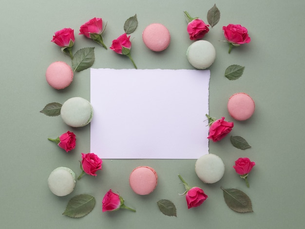 Romantisch mooi frame van macarons en rozen op groene achtergrond. Plat leggen. Bovenaanzicht