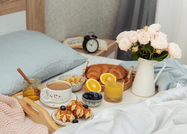 Romantisch ontbijt met koffie, wafels, jus d'orange en rozenbloemen.