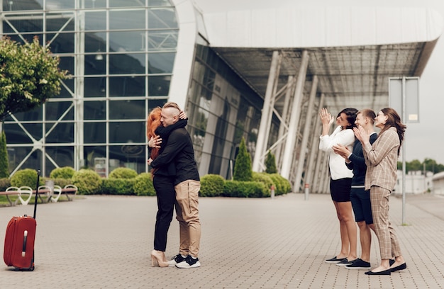 Romantisch paar dat zich dichtbij de luchthaven met een koffer bevindt