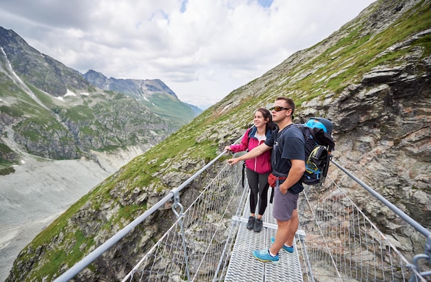 Romantisch paar dat zich op een brug bij rotsachtige achtergrond van Zwitserse Alpen bevindt