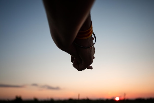 Romantisch paar hand in hand in zomer veld bij zonsondergang