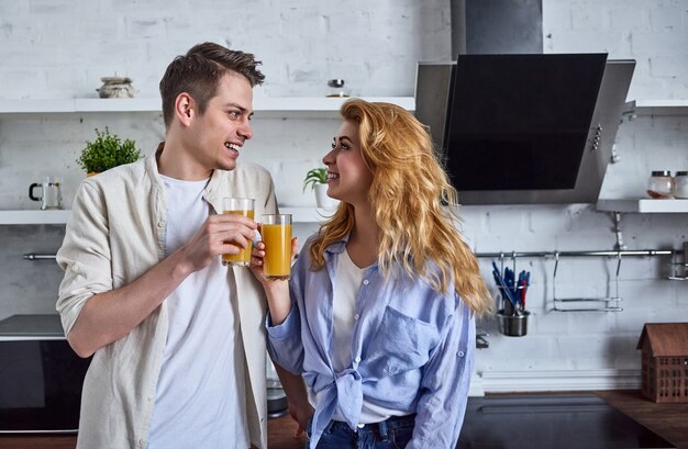 Romantisch paar in de huiskeuken. Mooie vrouw en aantrekkelijke man hebben een goede tijd om in de keuken te staan en sap te drinken.